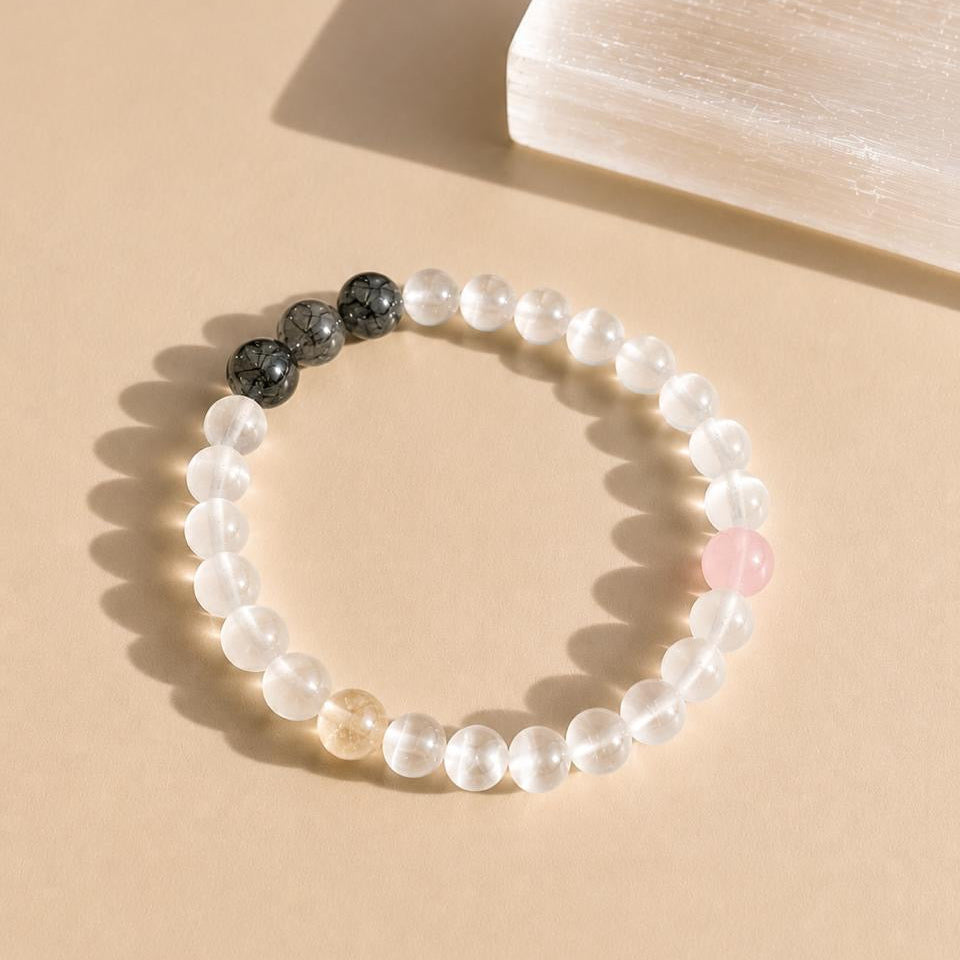 Beaded bracelet with black and selenite beads on a beige background