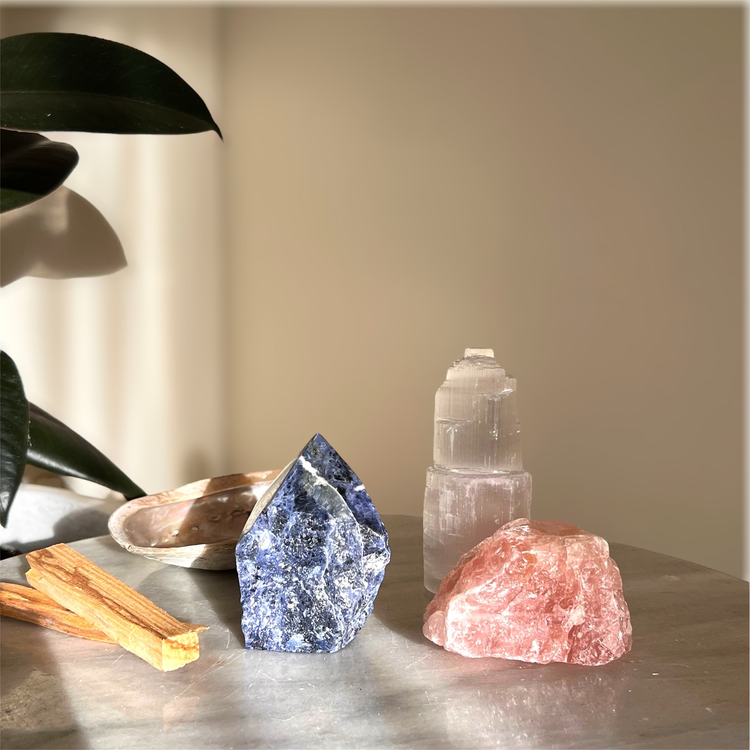 Crystal and stone collection on a reflective surface with a neutral background