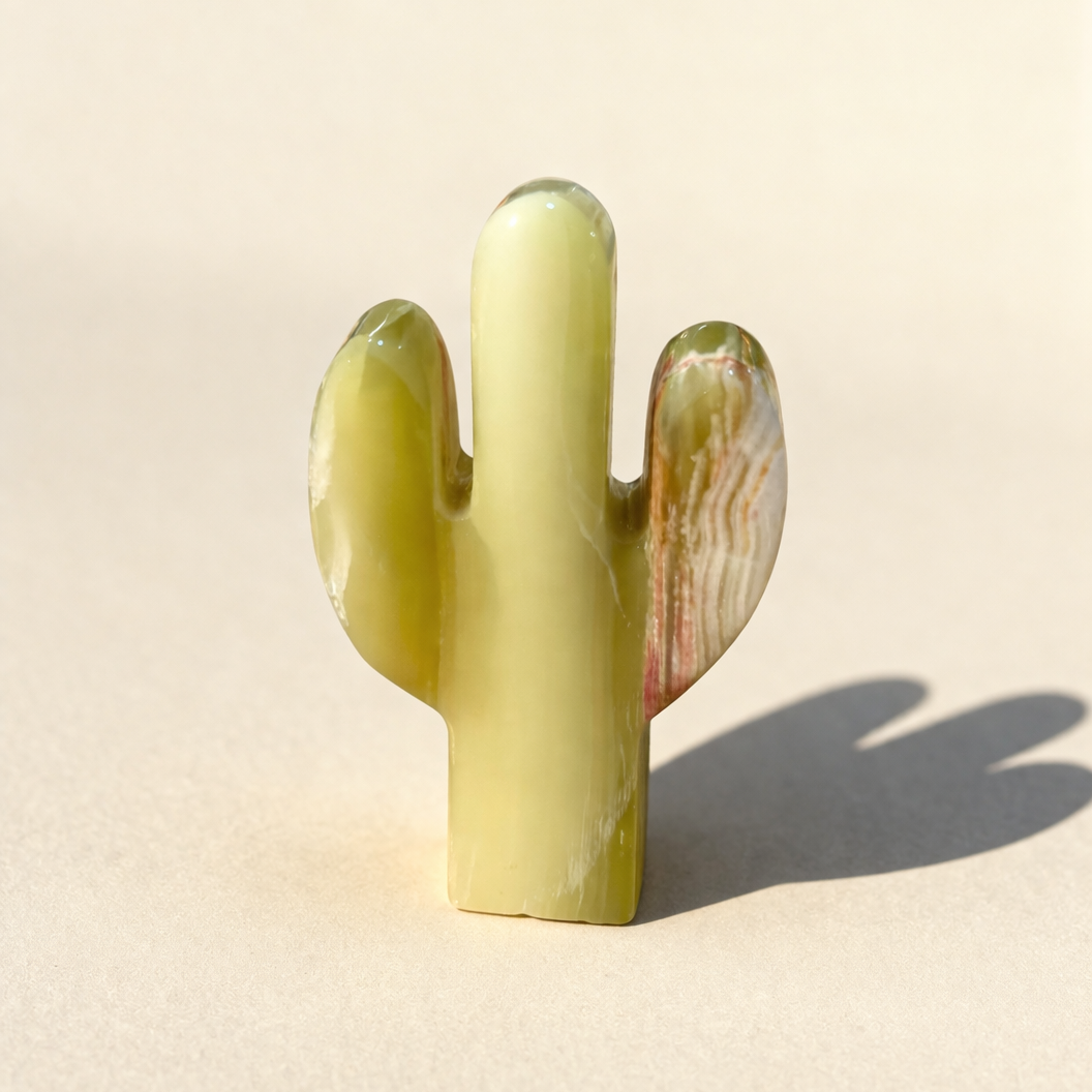Green onyx cactus-shaped crystal on a beige background