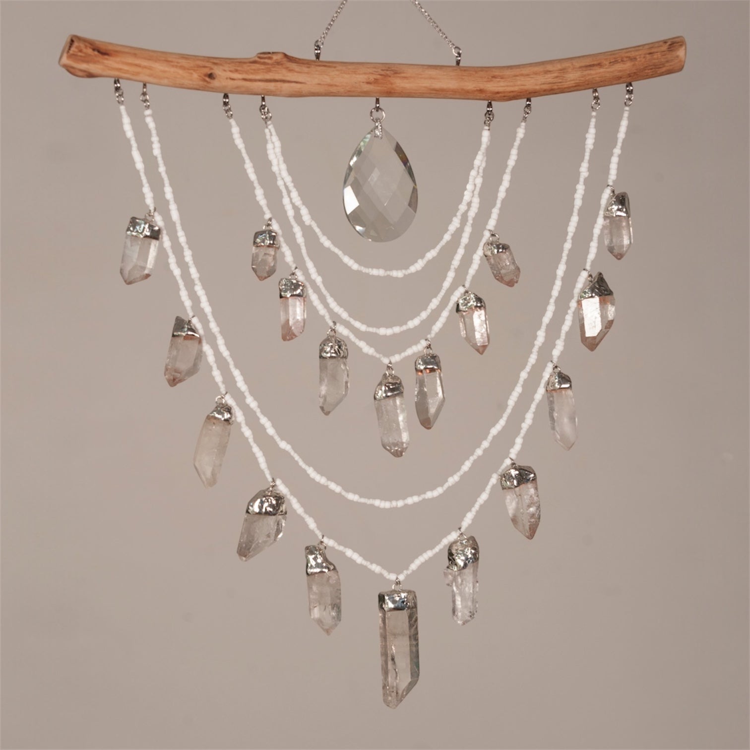 Crystal chandelier with hanging crystals and a wooden branch on a plain background