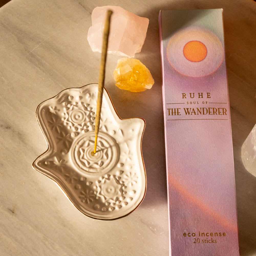 Hamsa Incense holder with incense stick and 'RUHE' eco incense packaging on a wooden surface