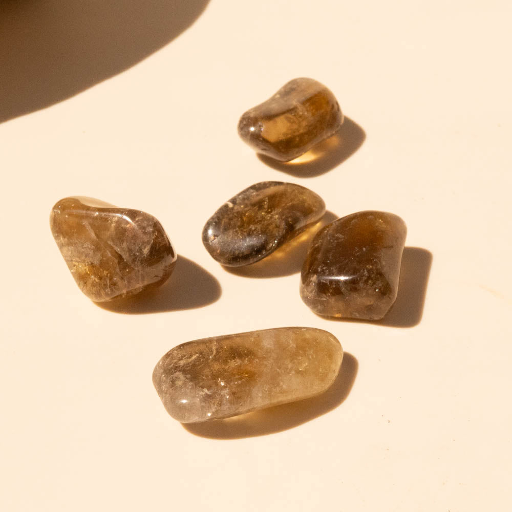Kundalini Citrine Tumbled Stones on a beige surface with soft shadows