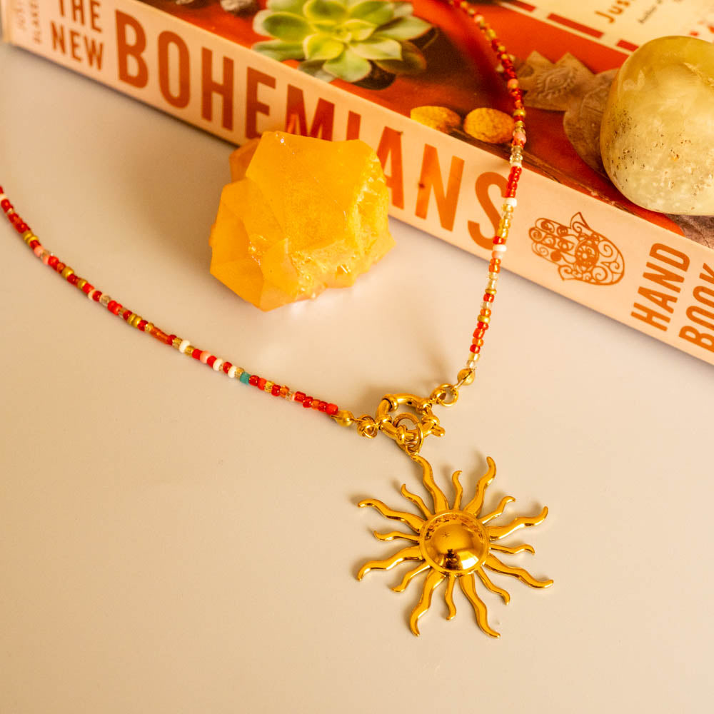 island sun charm red bead necklace on book display