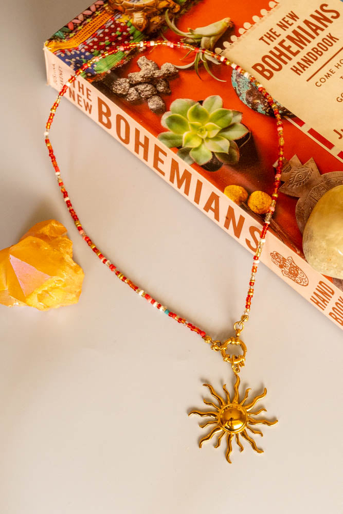 island sun charm red bead necklace on book display