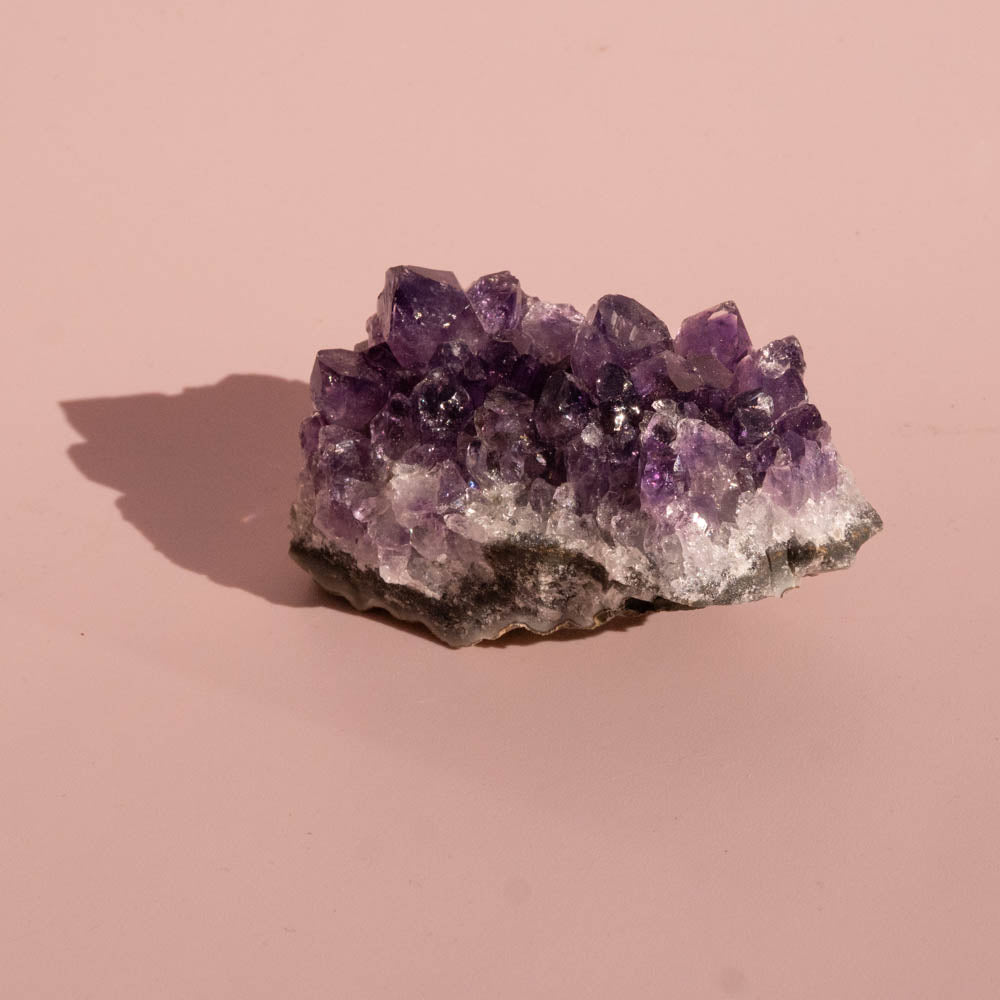 Amethyst crystal cluster on a pink background