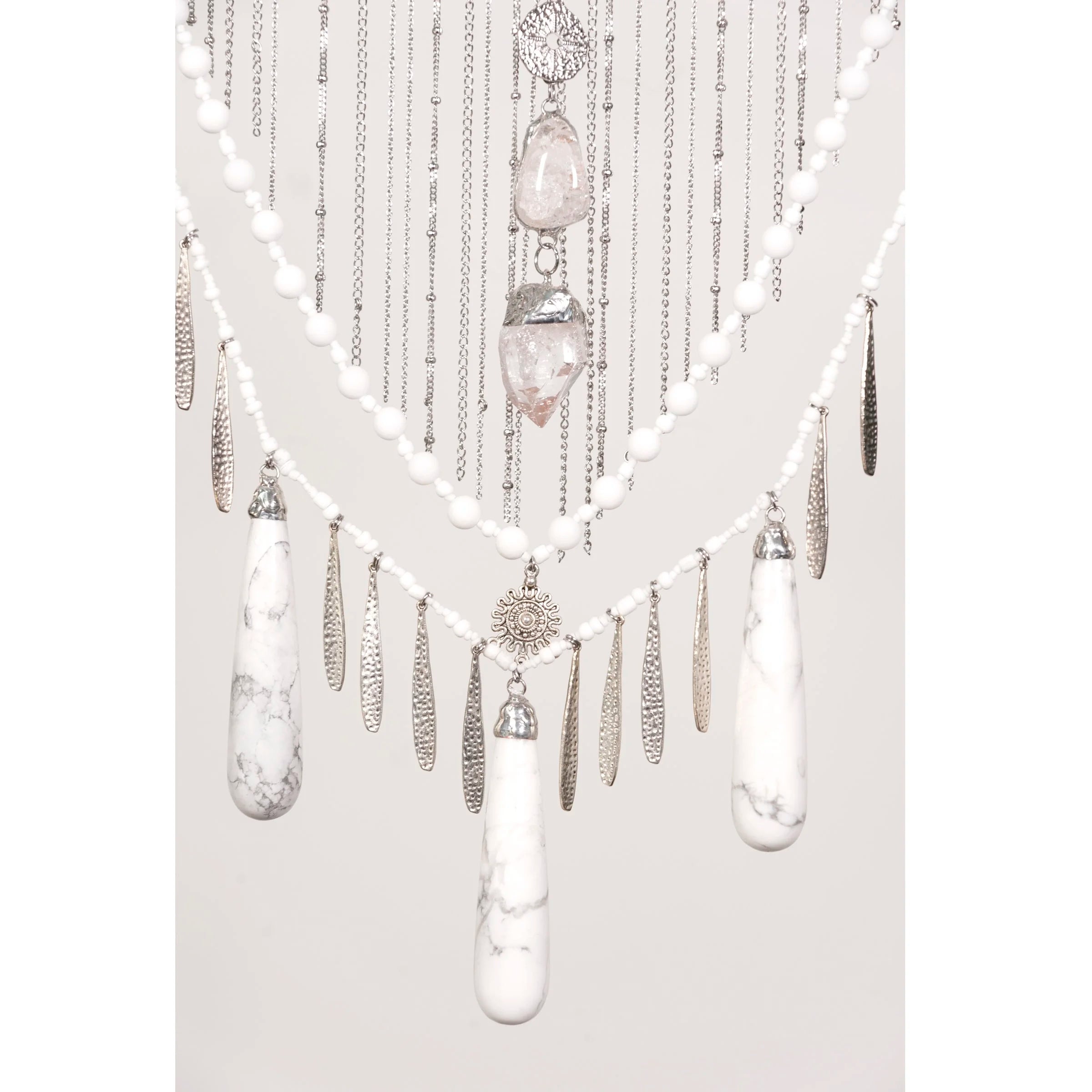Decorative wall hanging with Howlite with Quartz crystals and beads on a white background
