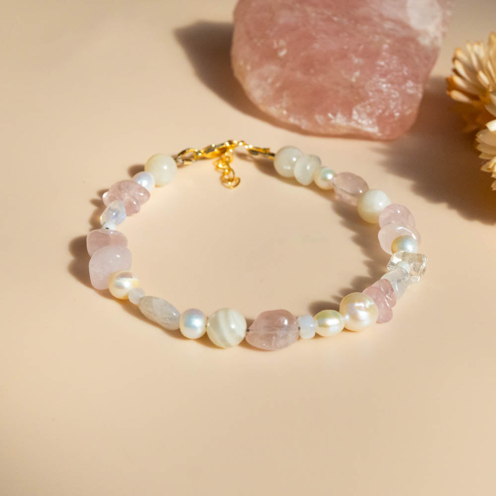 Beaded bracelet with rose quartz crystals and fresh water pearls on a beige background