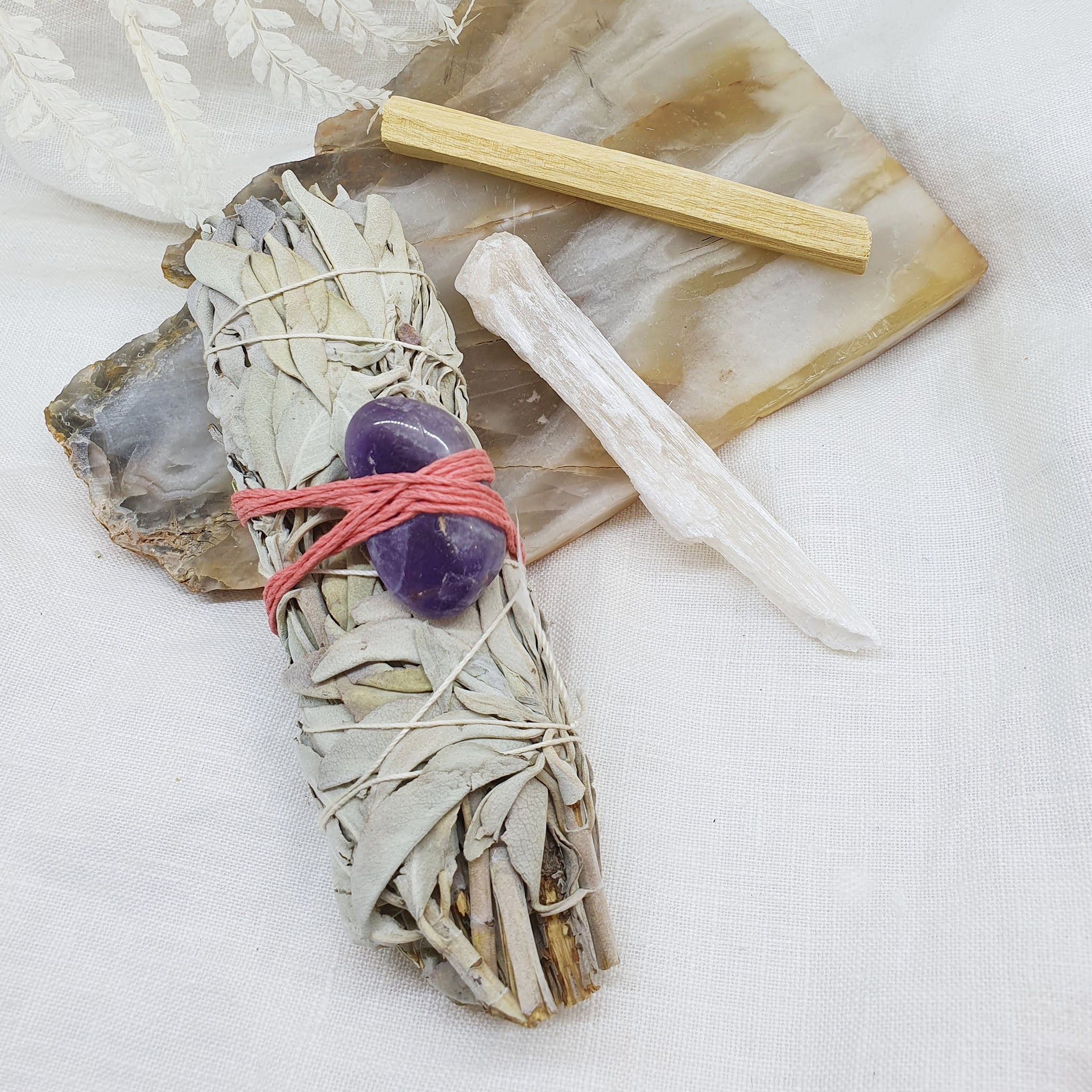 white sage smudge stick with amethyst, peach selenite and palo santo