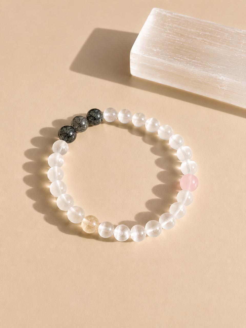 Beaded bracelet with black and selenite beads on a beige background
