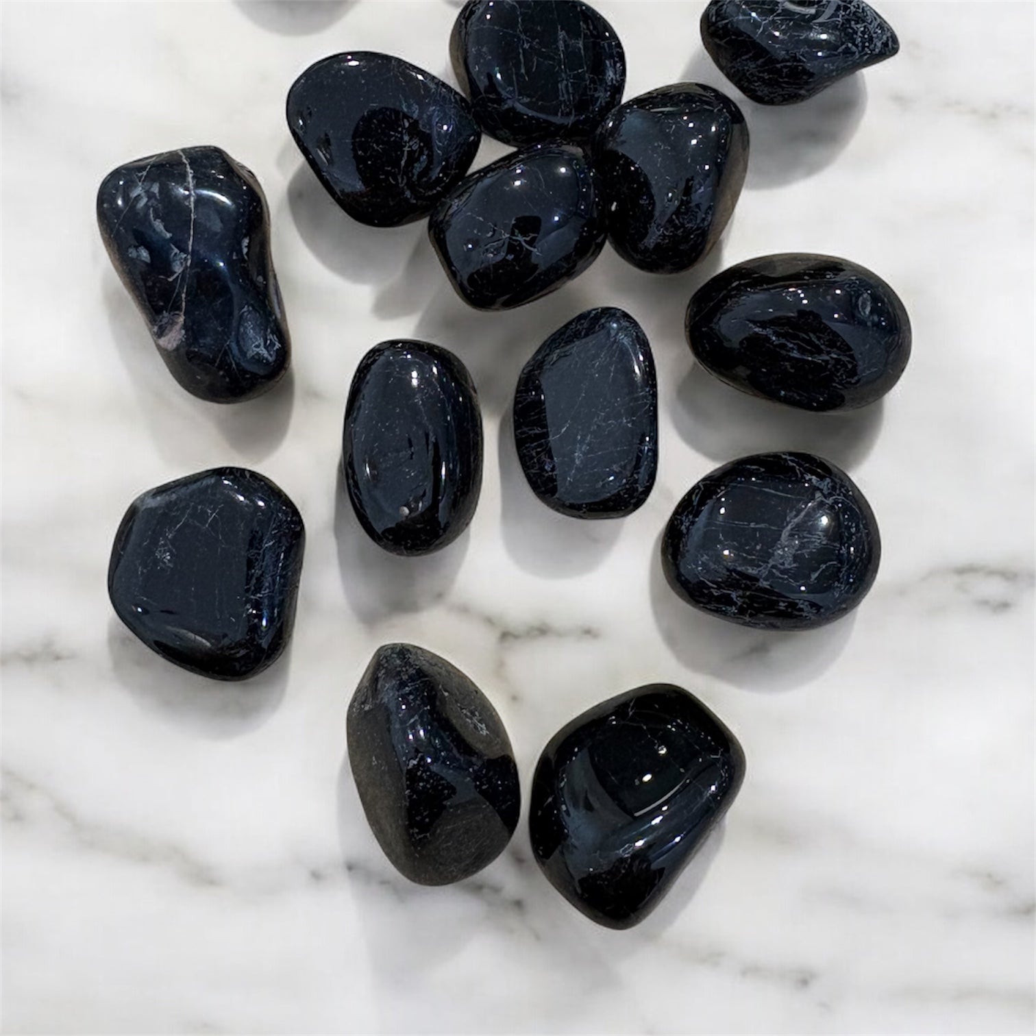 Black Tourmaline Tumbled Stones on a white marble surface