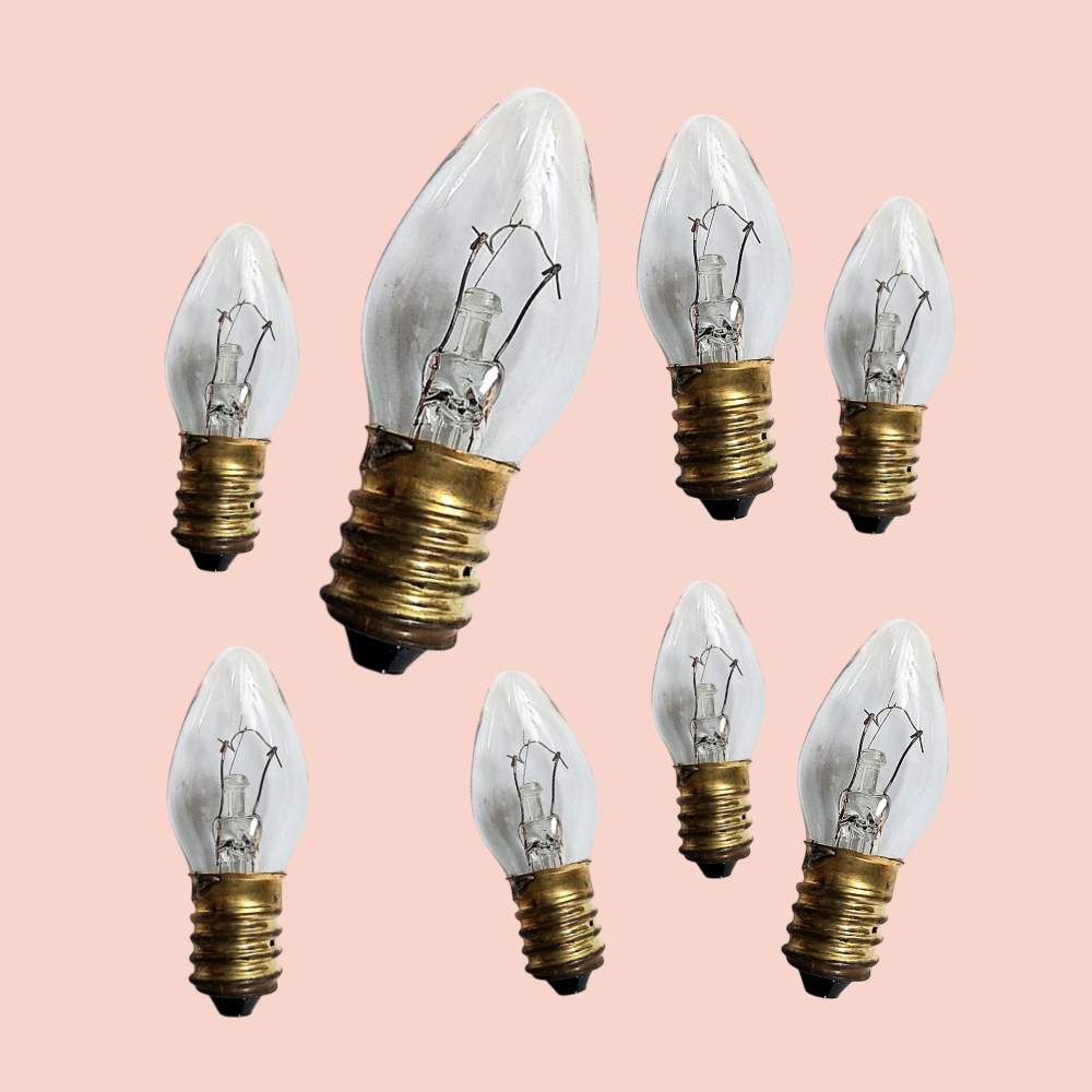 Set of eight clear light bulbs with gold bases on a pink background