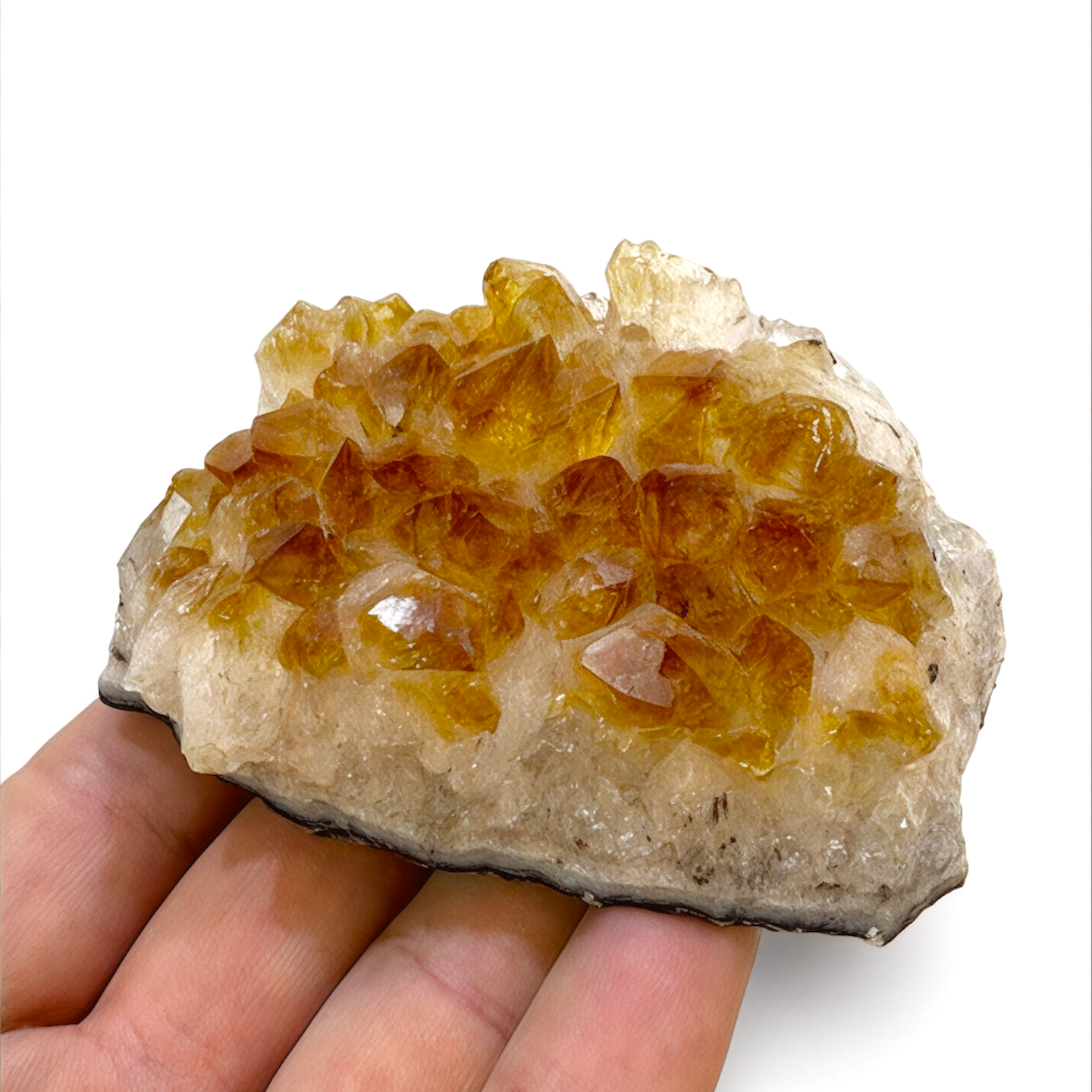 Hand holding a crystal with citrine crystals on a white background