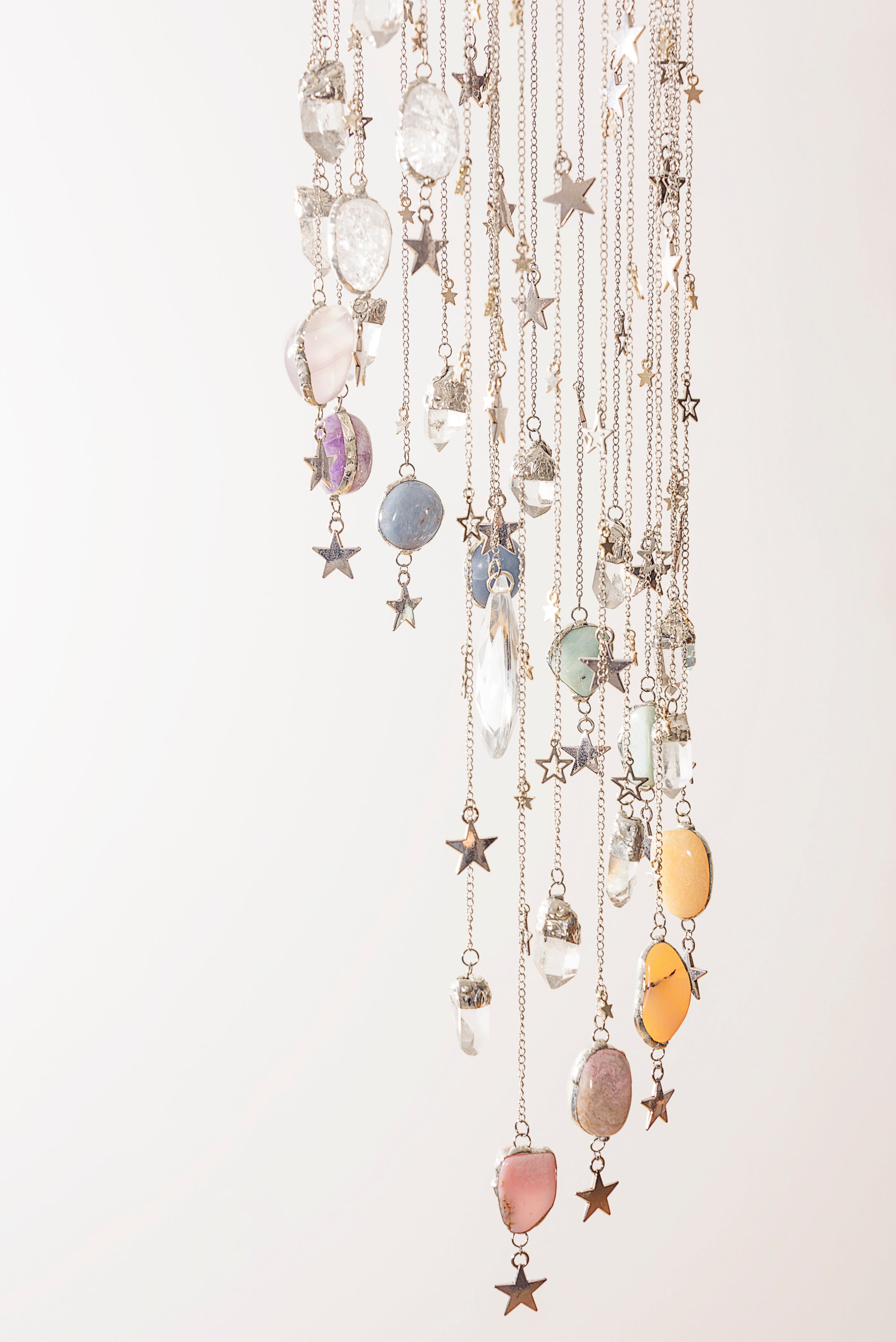 Decorative crystal hanging mobile with stars and colourful stones on a white background