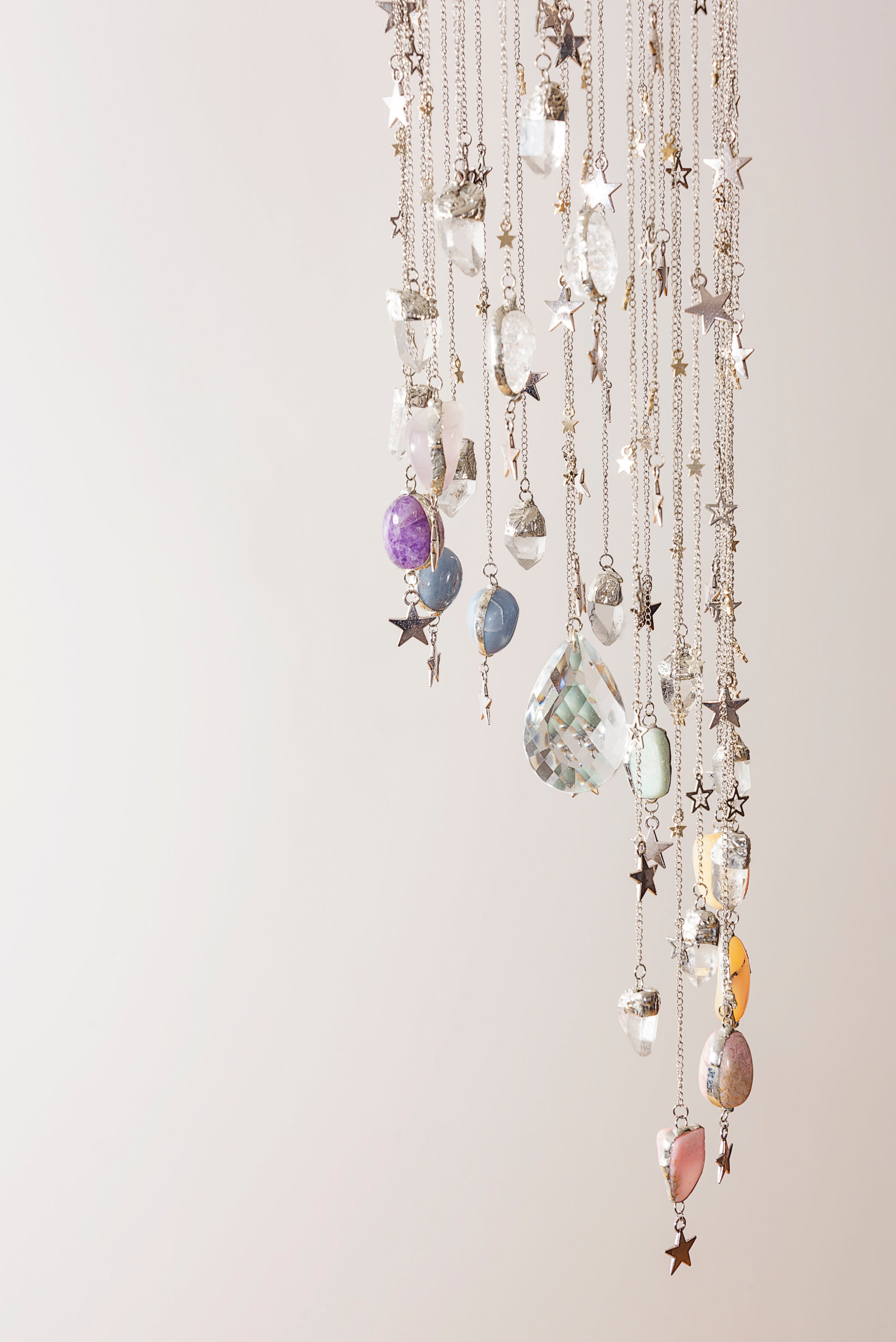 Decorative crystal hanging mobile with stars and colourful stones on a white background