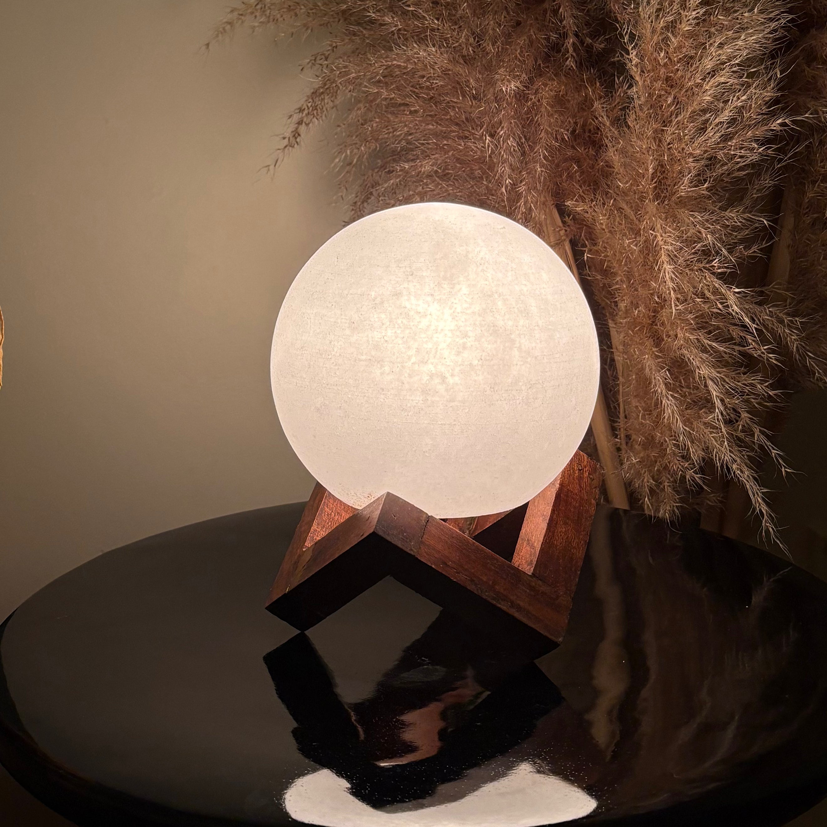 Spherical white salt lamp on a wooden stand with decorative plant in the background
