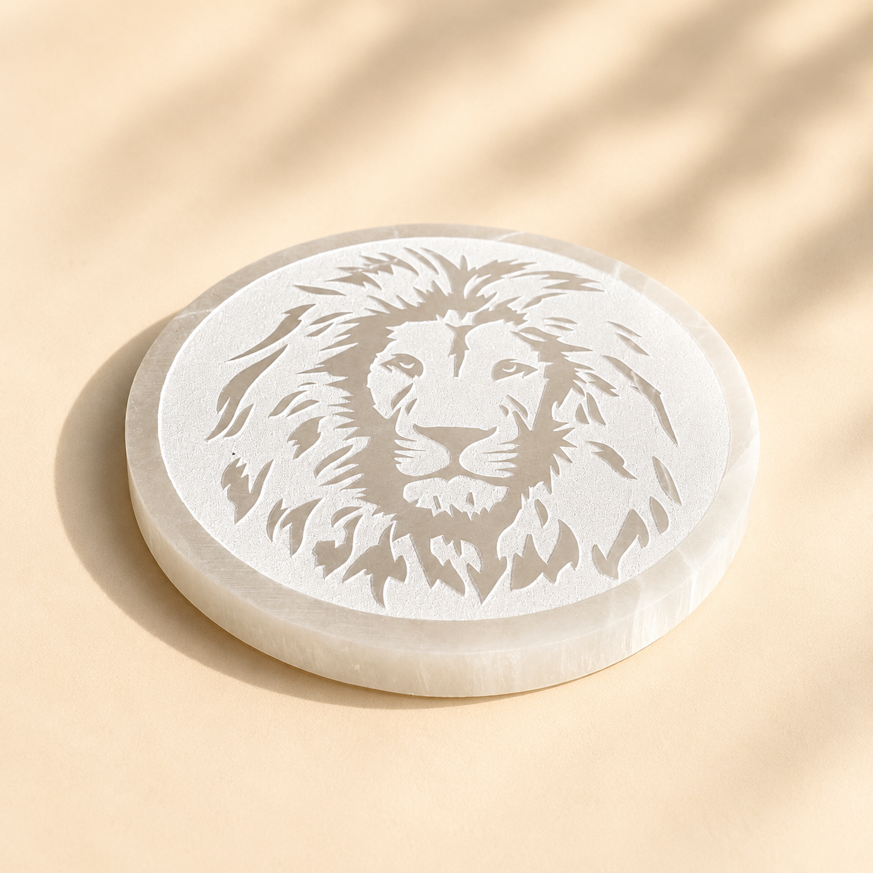 Round selenite crystal charging plate  with a lion engraving on a beige background