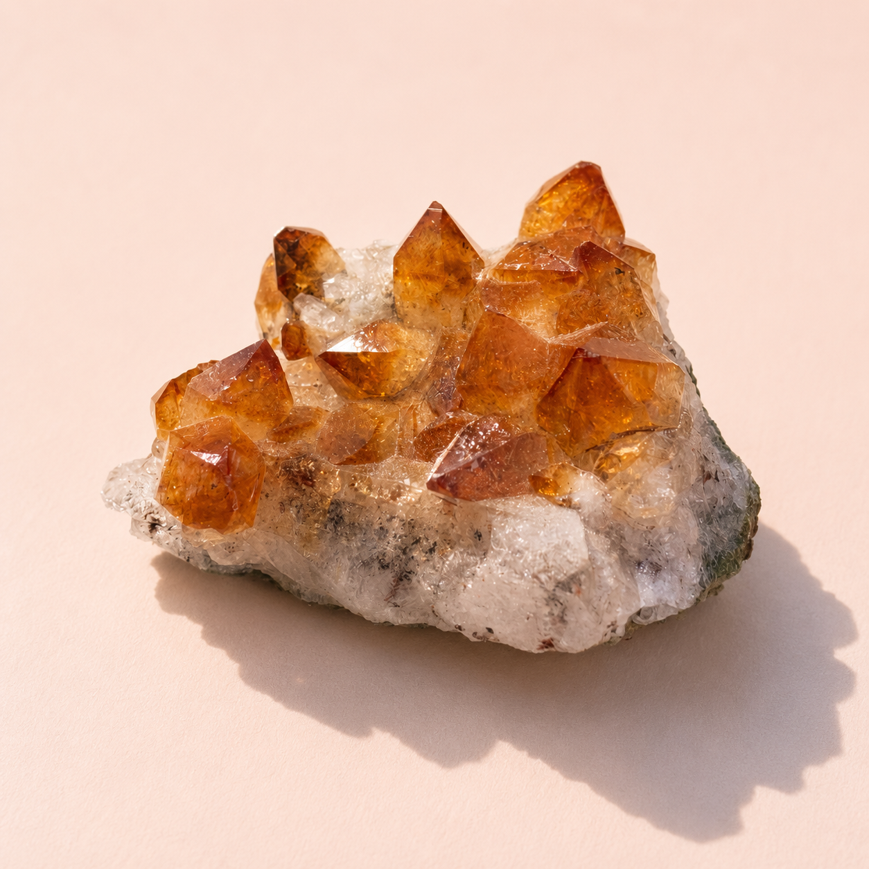 Citrine crystal cluster on a light pink background