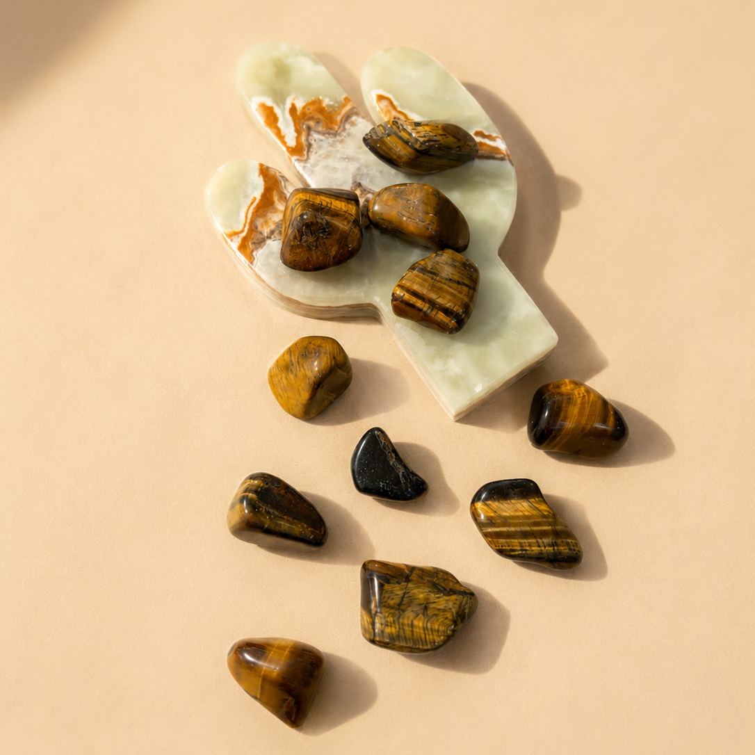 Tiger's Eye Tumbled stones on a white stone surface with a beige background
