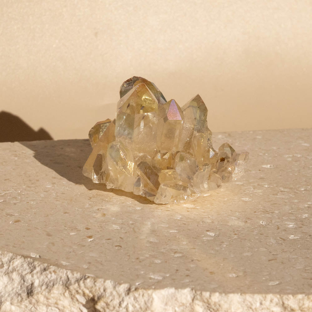 Angel Aura crystal cluster on a beige surface with a neutral background