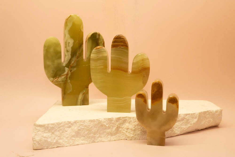 Green Onyx cactus sculpture on a stone base against a pink background