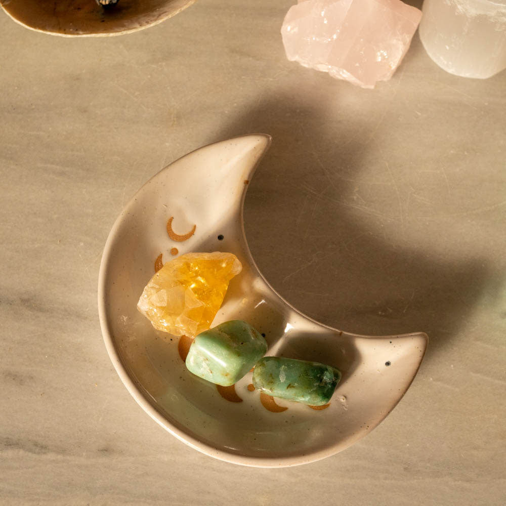 Decorative moon-shaped dish with crystals on marble surface