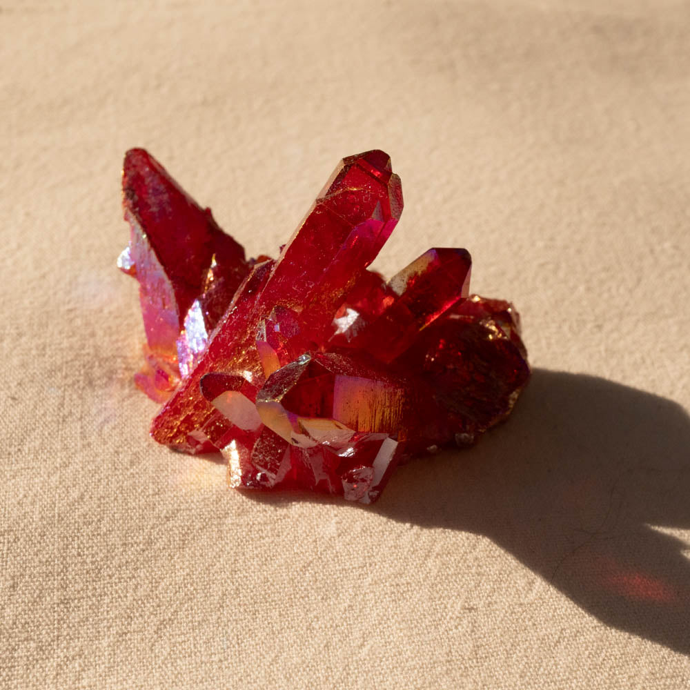 Ruby Aura crystal cluster on a beige surface