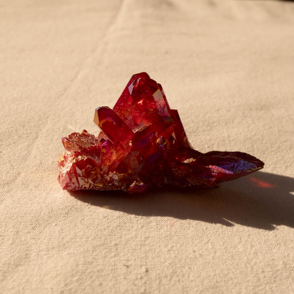 Ruby Aura crystal cluster on a beige surface