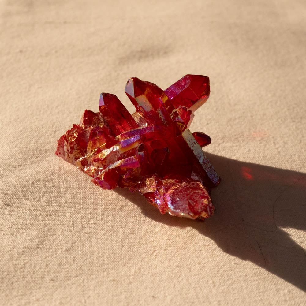 Ruby Aura crystal cluster on a beige surface
