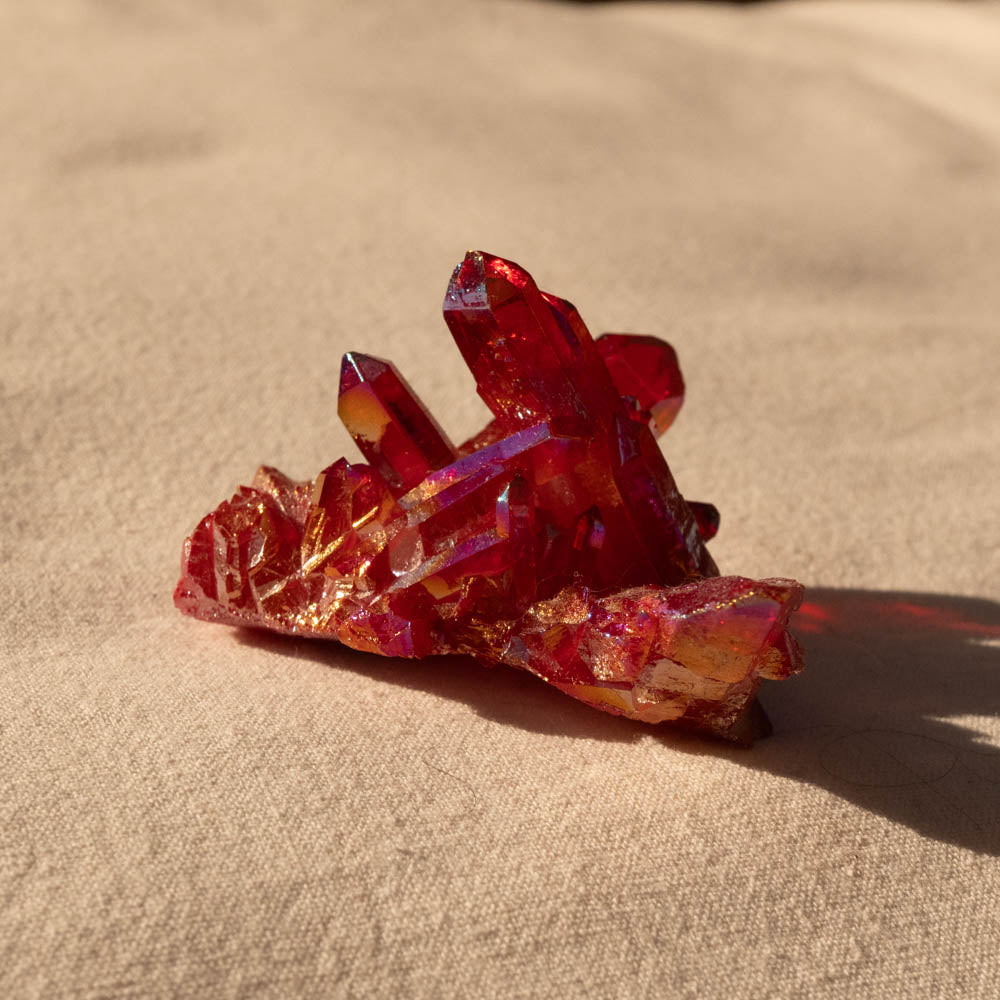 Ruby Aura crystal cluster on a beige surface