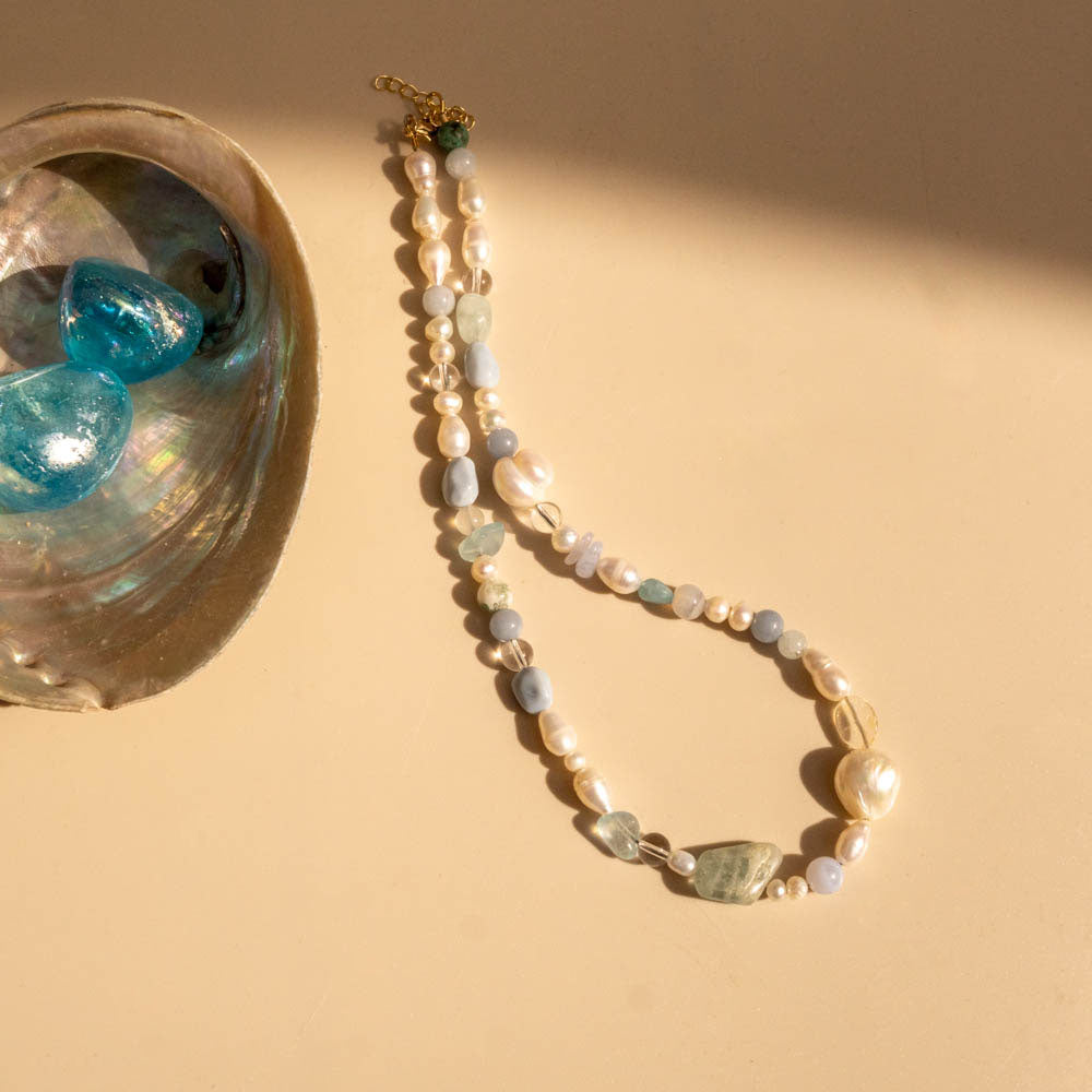 Pearl necklace with blue stones on a beige background