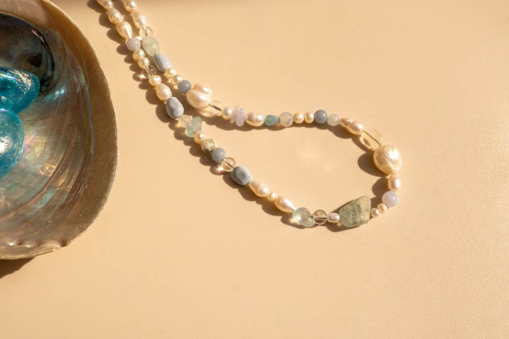 Pearl bracelet on a beige background with a shell