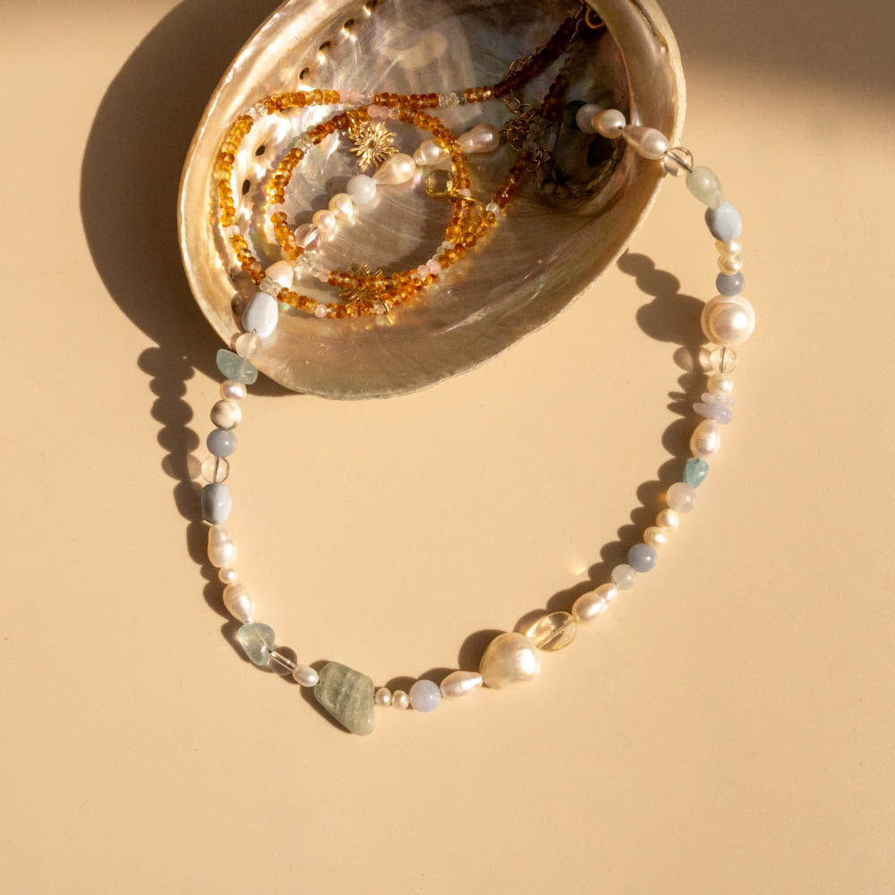 Pearl necklace with small stones on a beige surface