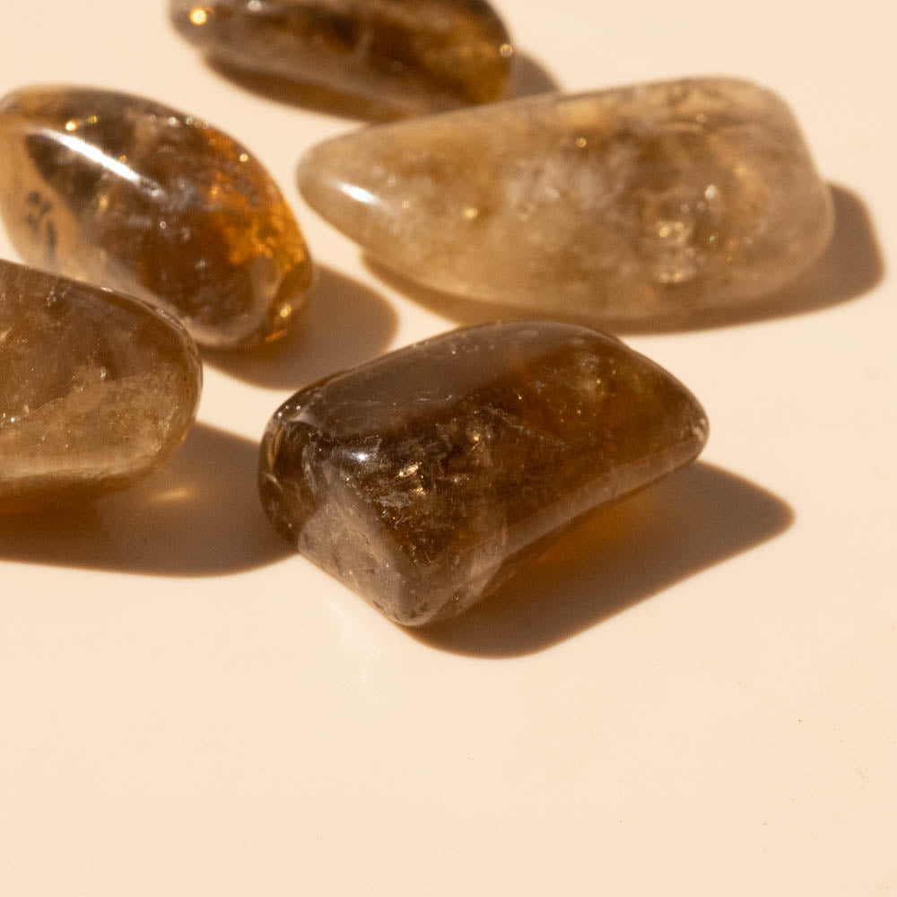 Close-up of translucent Kundalini Citrine Tumbled Stones on a beige background