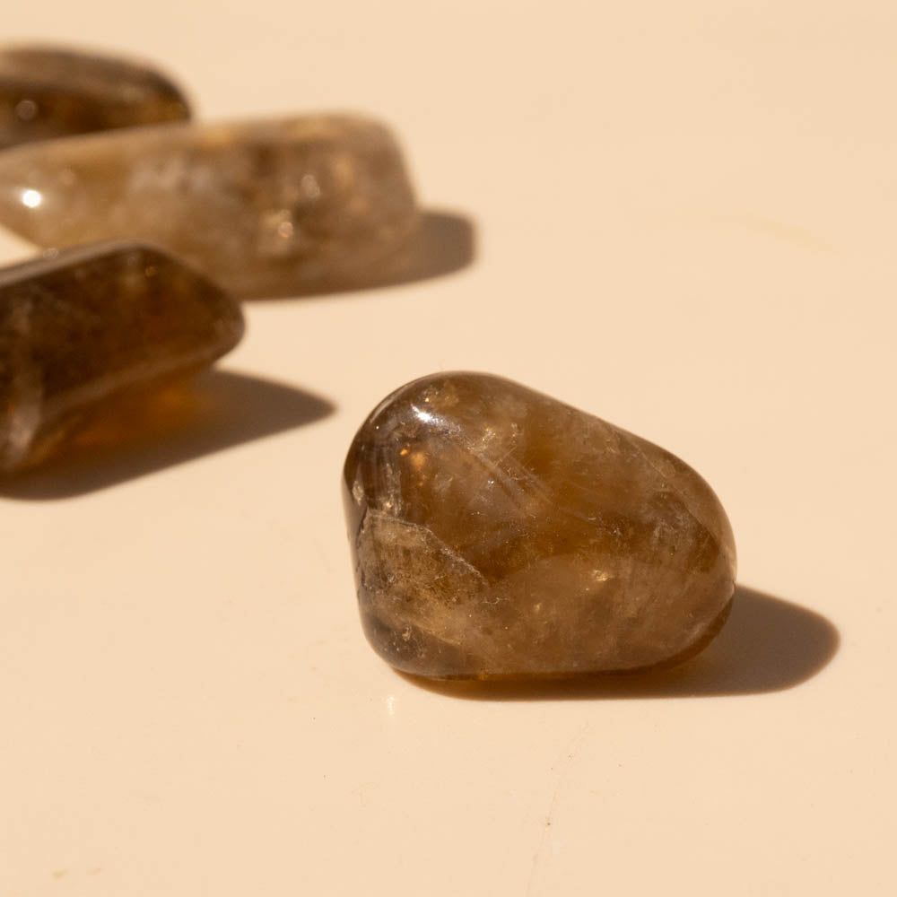 Close-up of Kundalini Citrine Tumbled Stones on a beige surface