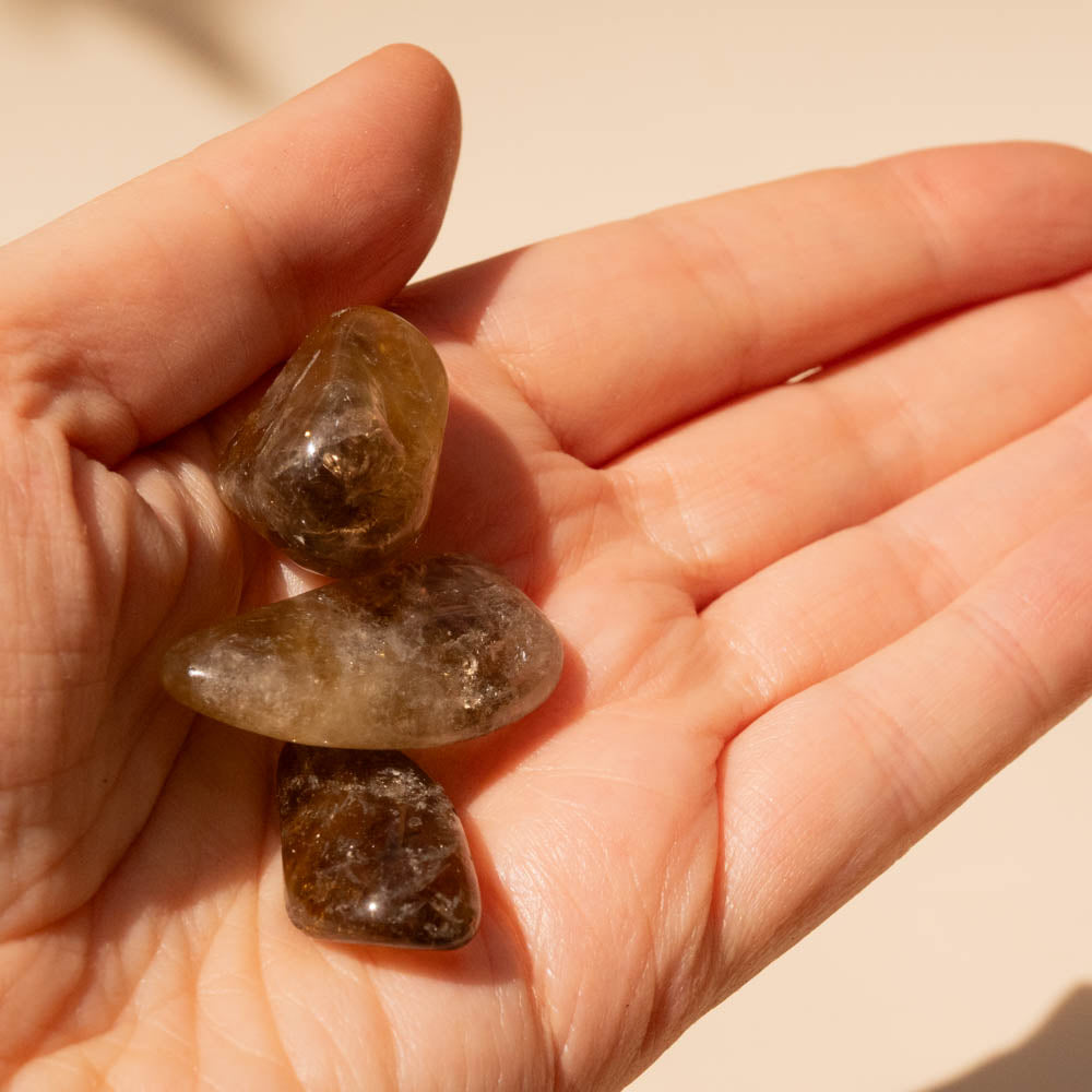 Kundalini Citrine Tumbled Stones held in a person's palm against a neutral background