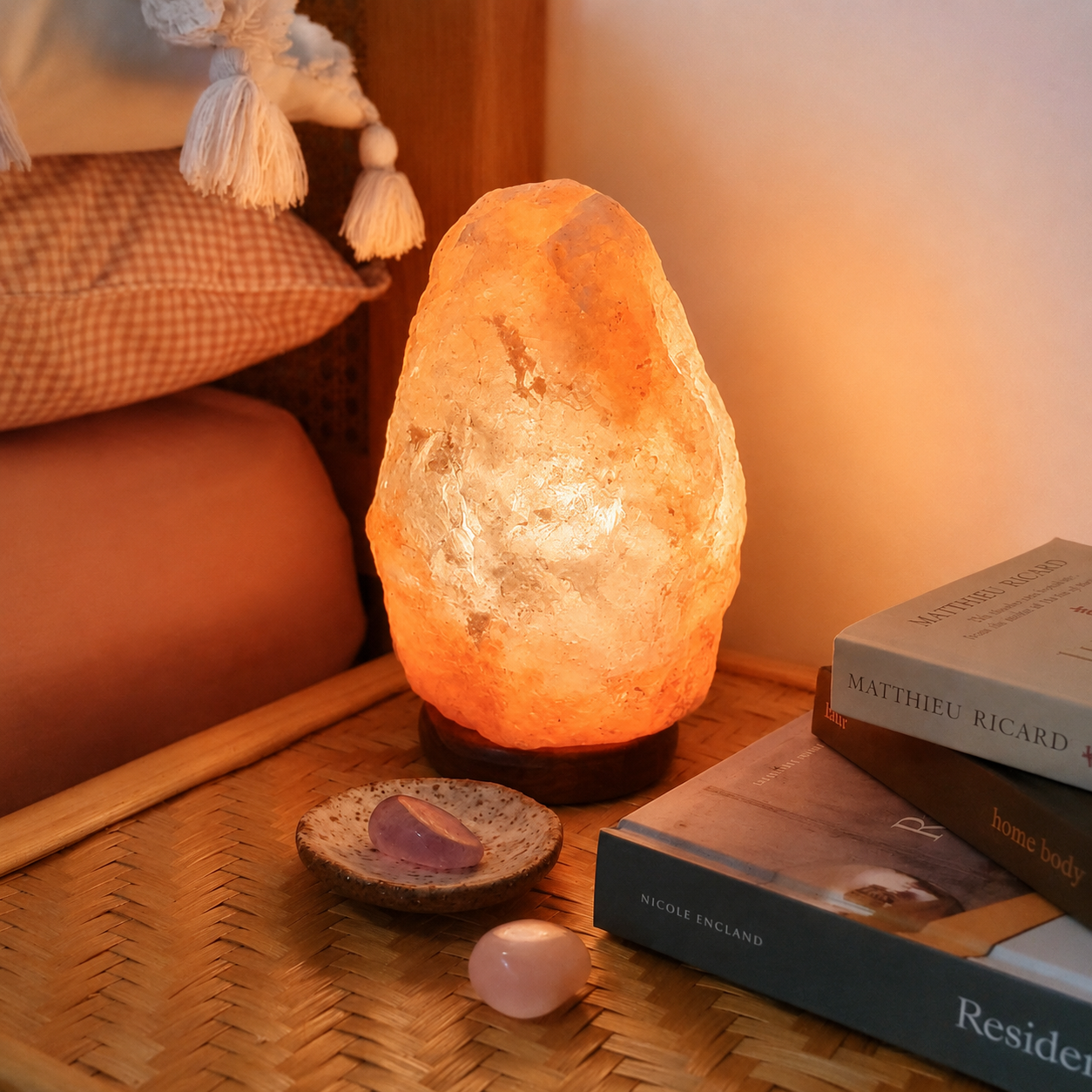 Himalayan salt lamp on a table with books and a small dish