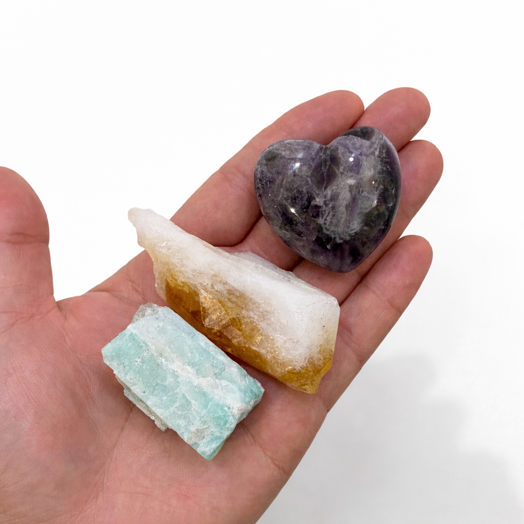 Hand holding three different crystal stones Amethyst, Citrine and Amazonite on a white background