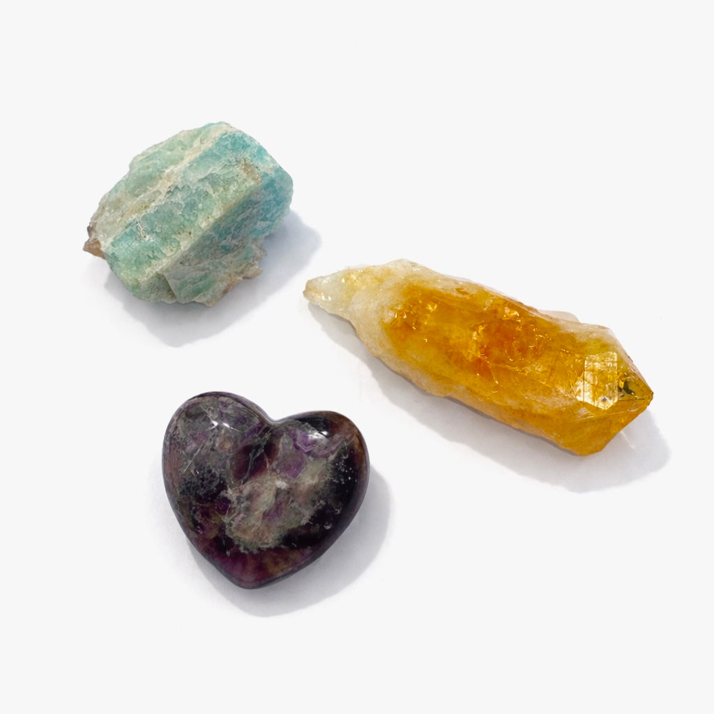Three crystals; Amethyst Heart, Amazonite Rough and Citrine Raw Point on a white background