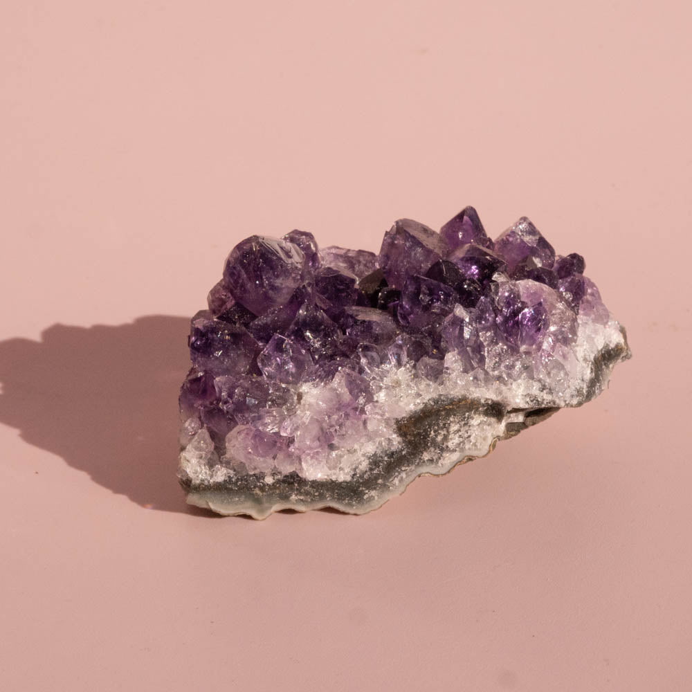 Amethyst crystal cluster on a pink background