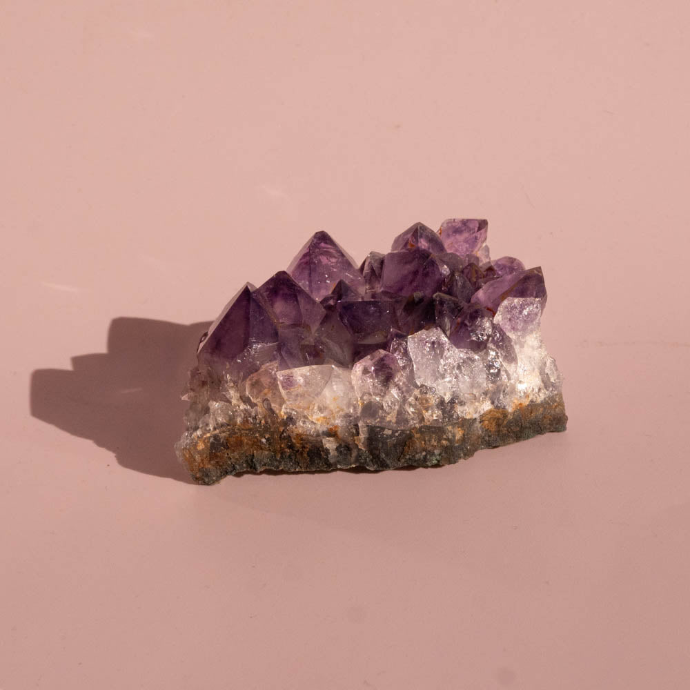 Amethyst crystal cluster on a pink background