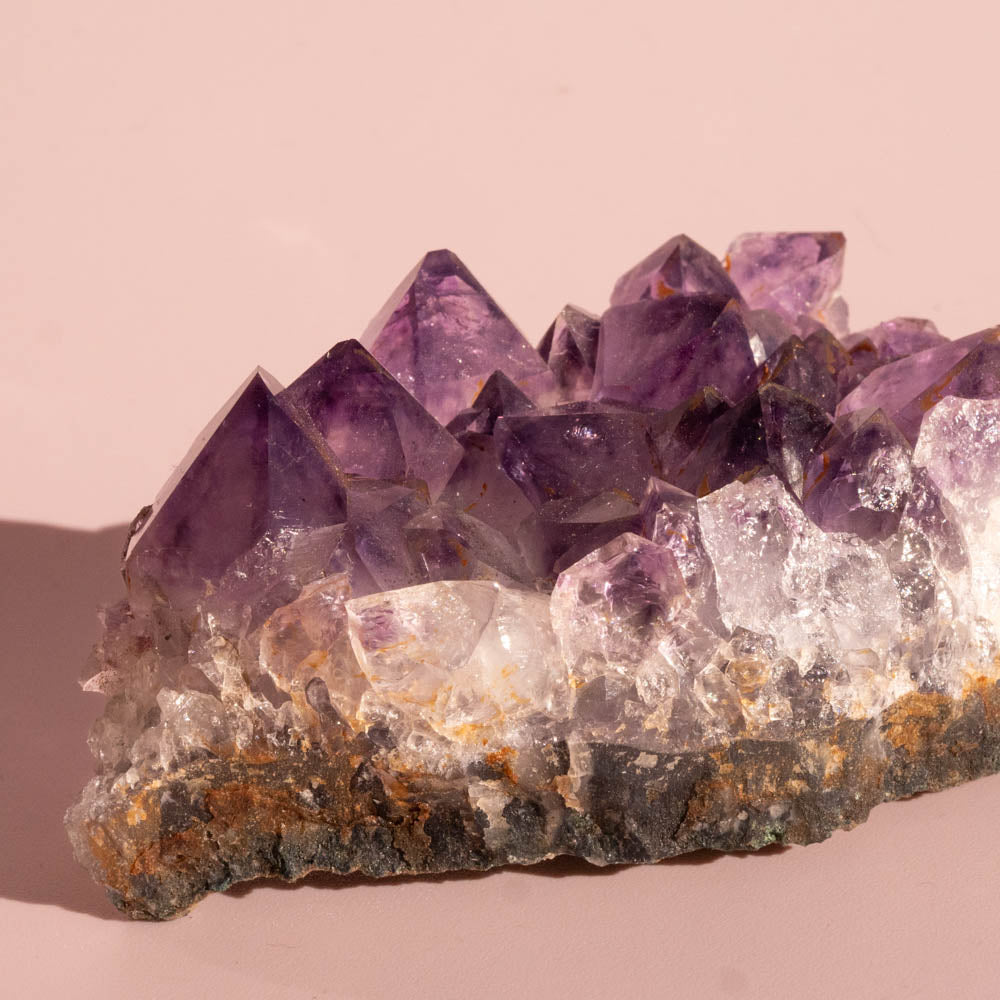 Amethyst crystal cluster on a pink background