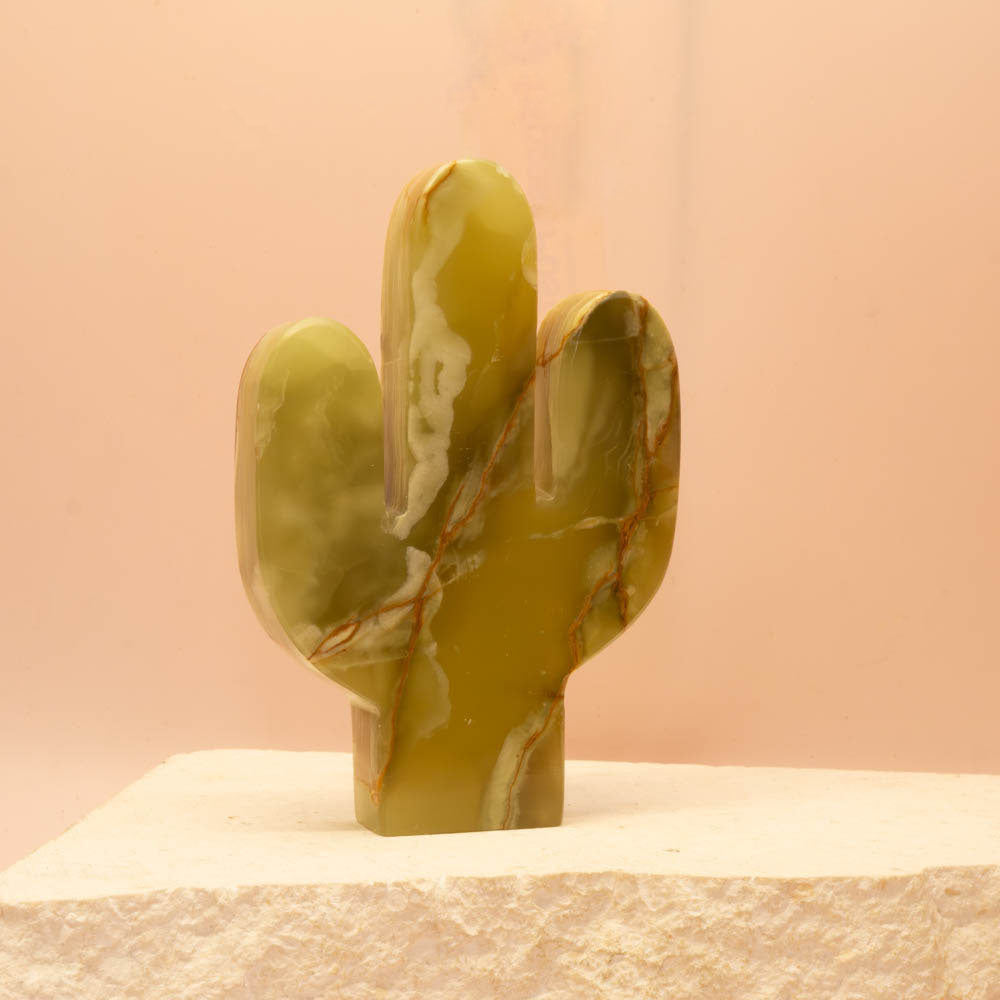 Marble-textured Green Onyx_cactus sculpture on a beige surface with a pink background