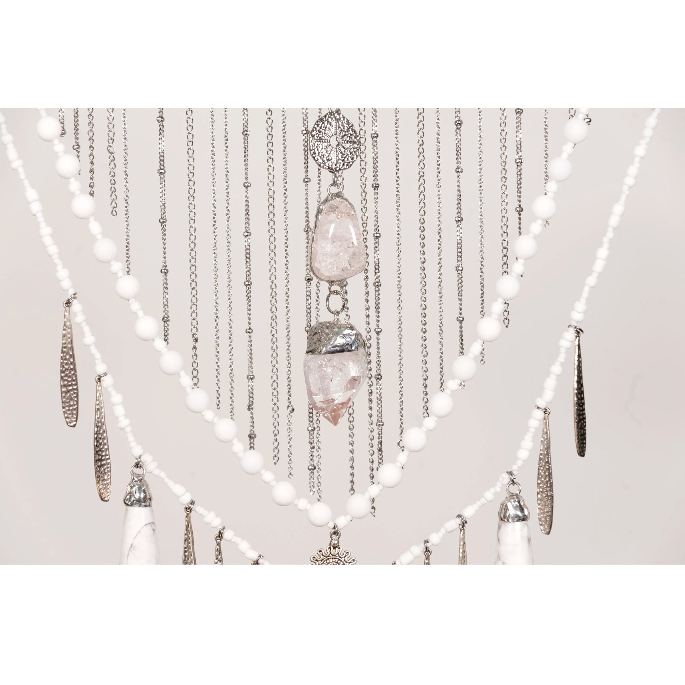 Decorative wall hanging with Howlite with Quartz crystals and beads on a white background