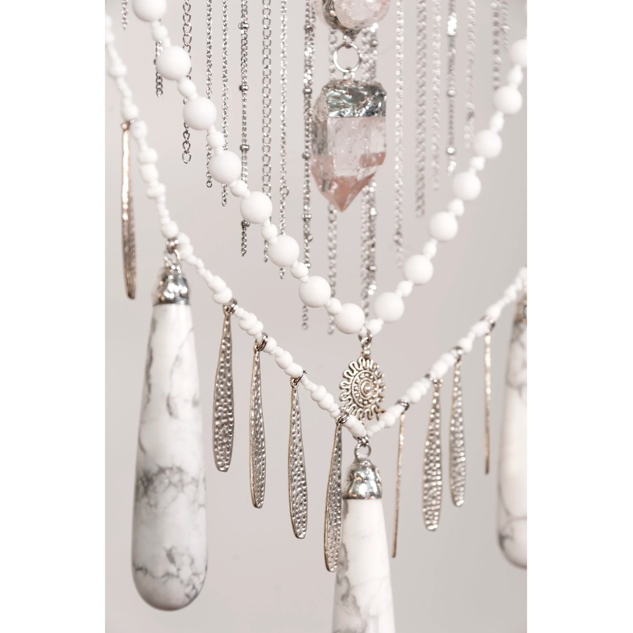 Decorative wall hanging with Howlite with Quartz crystals and beads on a white background