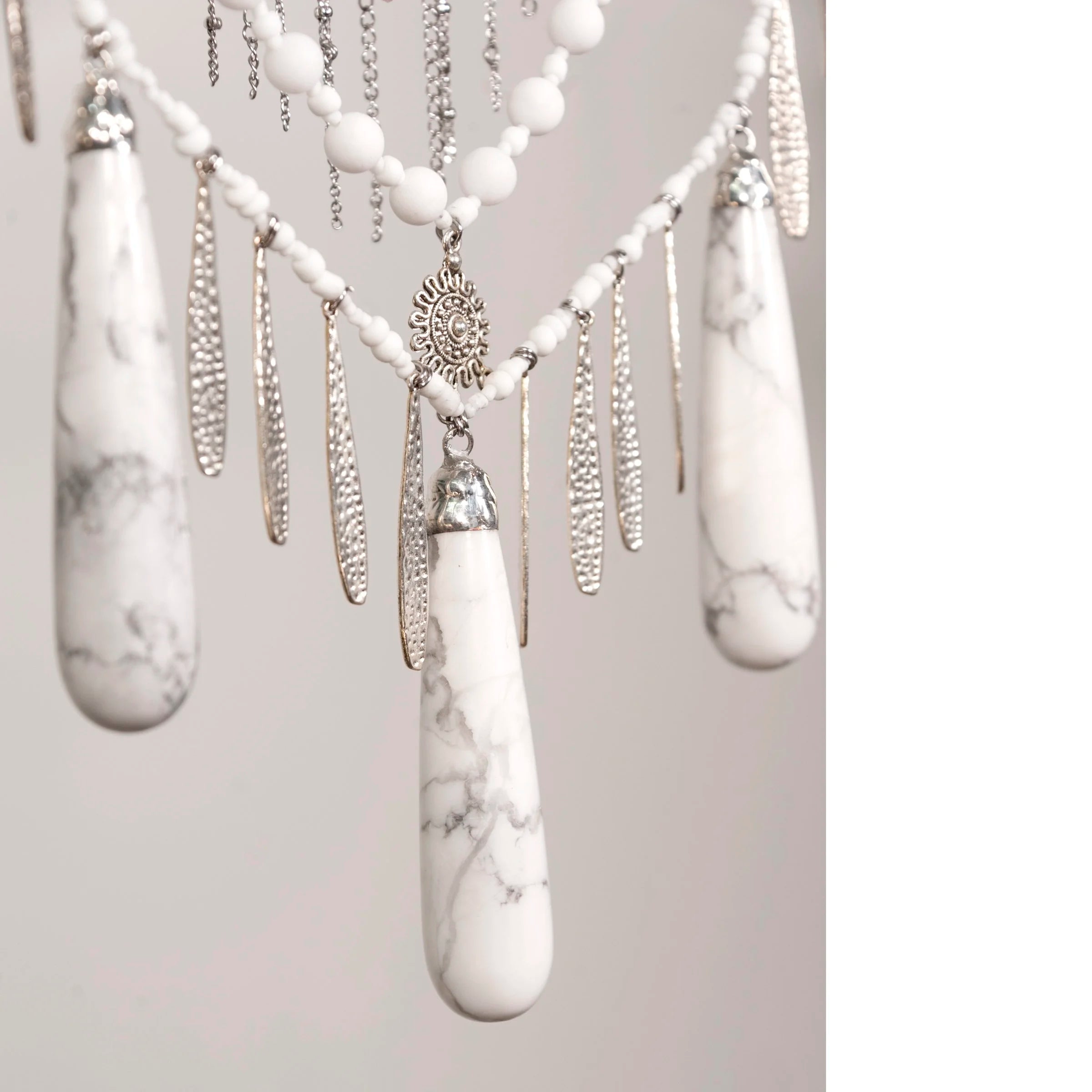 Decorative wall hanging with Howlite with Quartz crystals and beads on a white background
