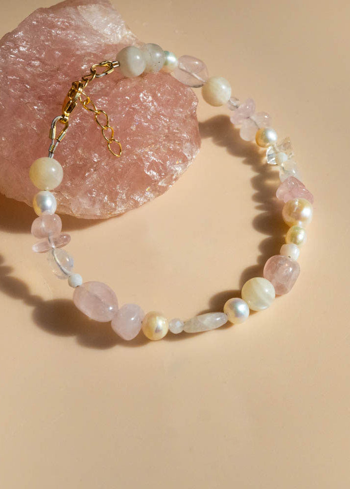 Beaded bracelet with rose quartz crystals and fresh water pearls on a beige background