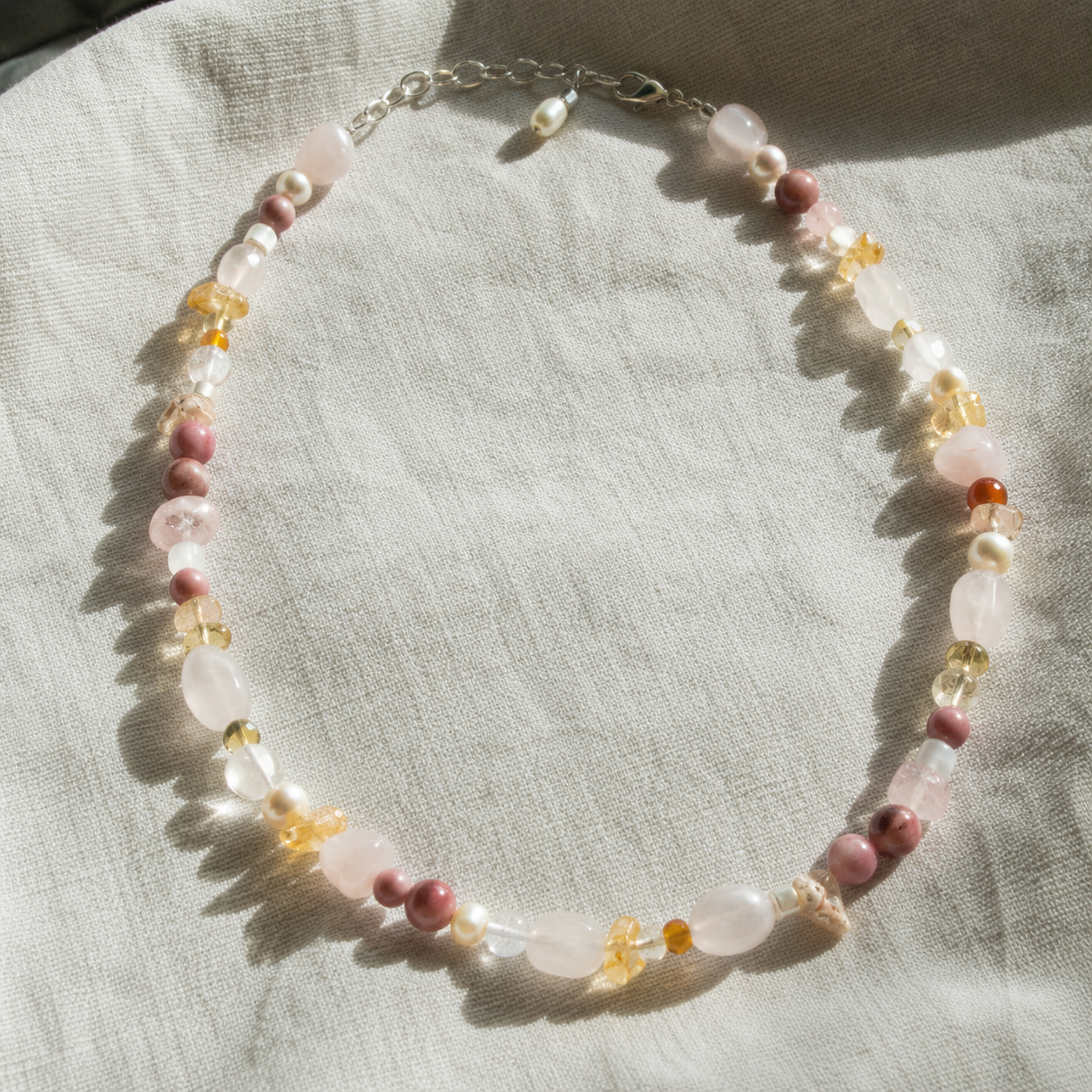Necklace with pink and yellow beads on a light fabric background