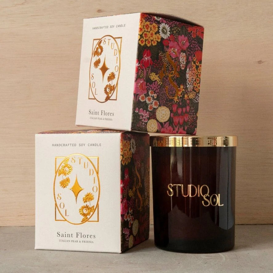Candle with decorative packaging and 'STUDIQSOL' branding on a wooden surface