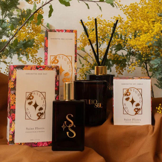 Decorative items including a black vase with sticks, boxes, and flowers on a beige surface.