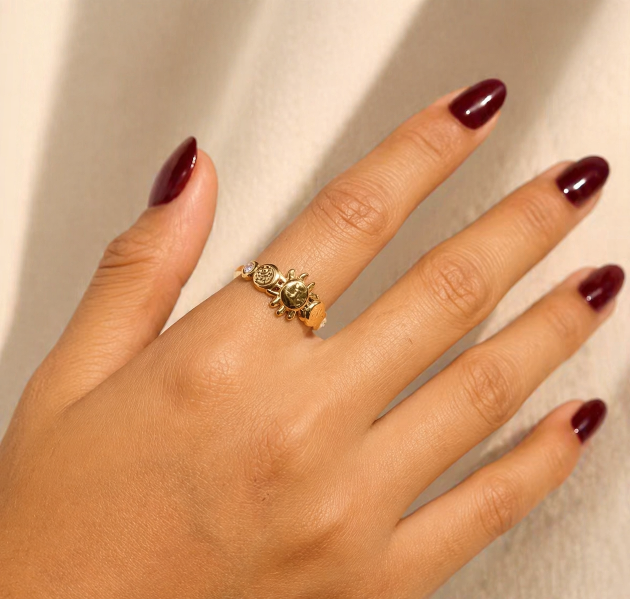 Hand wearing sun and moon gold ring on neatral background 